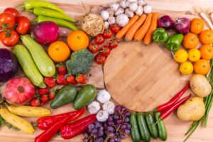 A family prepares a meal together with fresh fruits, vegetables, and dairy products on a kitchen counter.