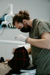 A family with young children sits together in a bright dental exam room, smiling as a dentist explains an X-ray.