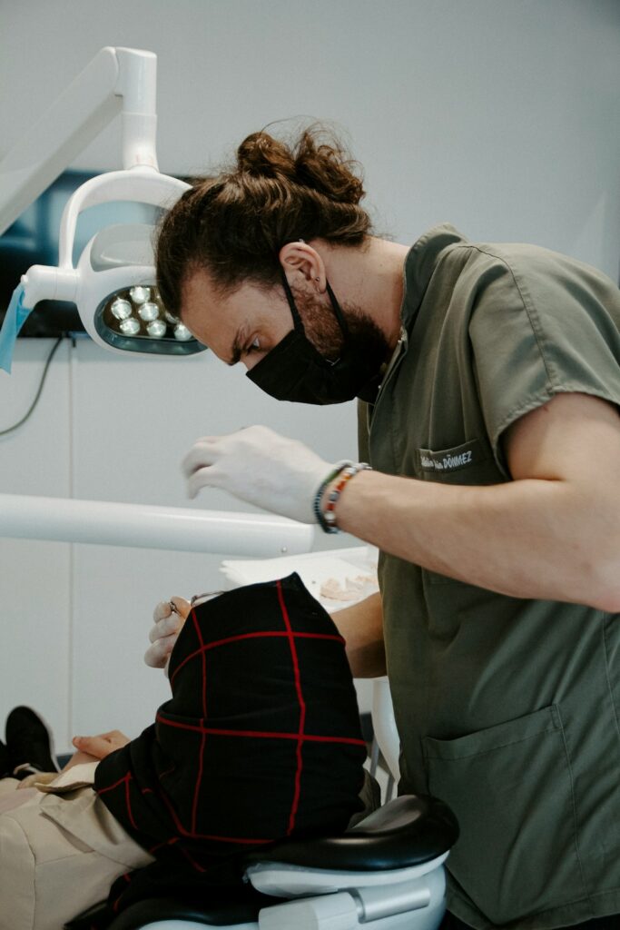 A family with young children sits together in a bright dental exam room, smiling as a dentist explains an X-ray.