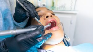 A close-up of a child showing their teeth to an adult in a well-lit home bathroom.